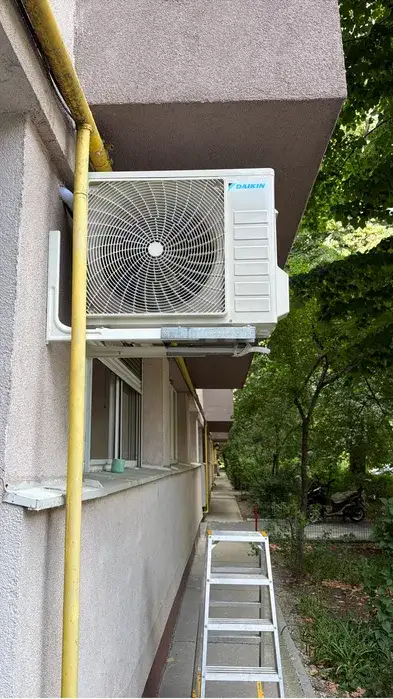 Unitatea Daikin pe console sub balcon, la distanță de conducta de gaz galbenă