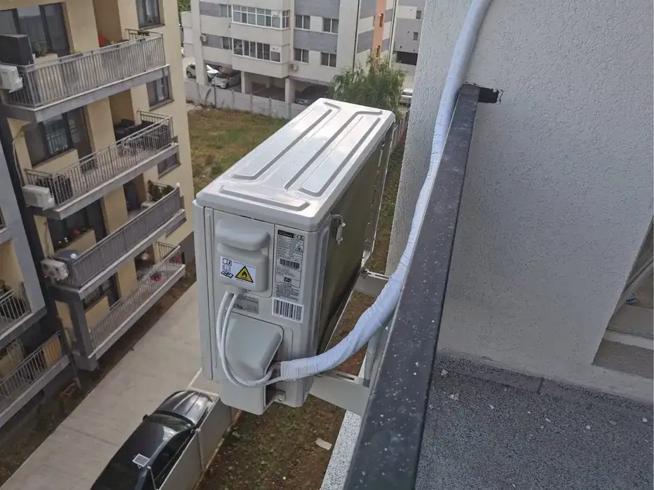 Unitatea exterioară pe consolă în afara balconului, cu traseul izolat pe perete